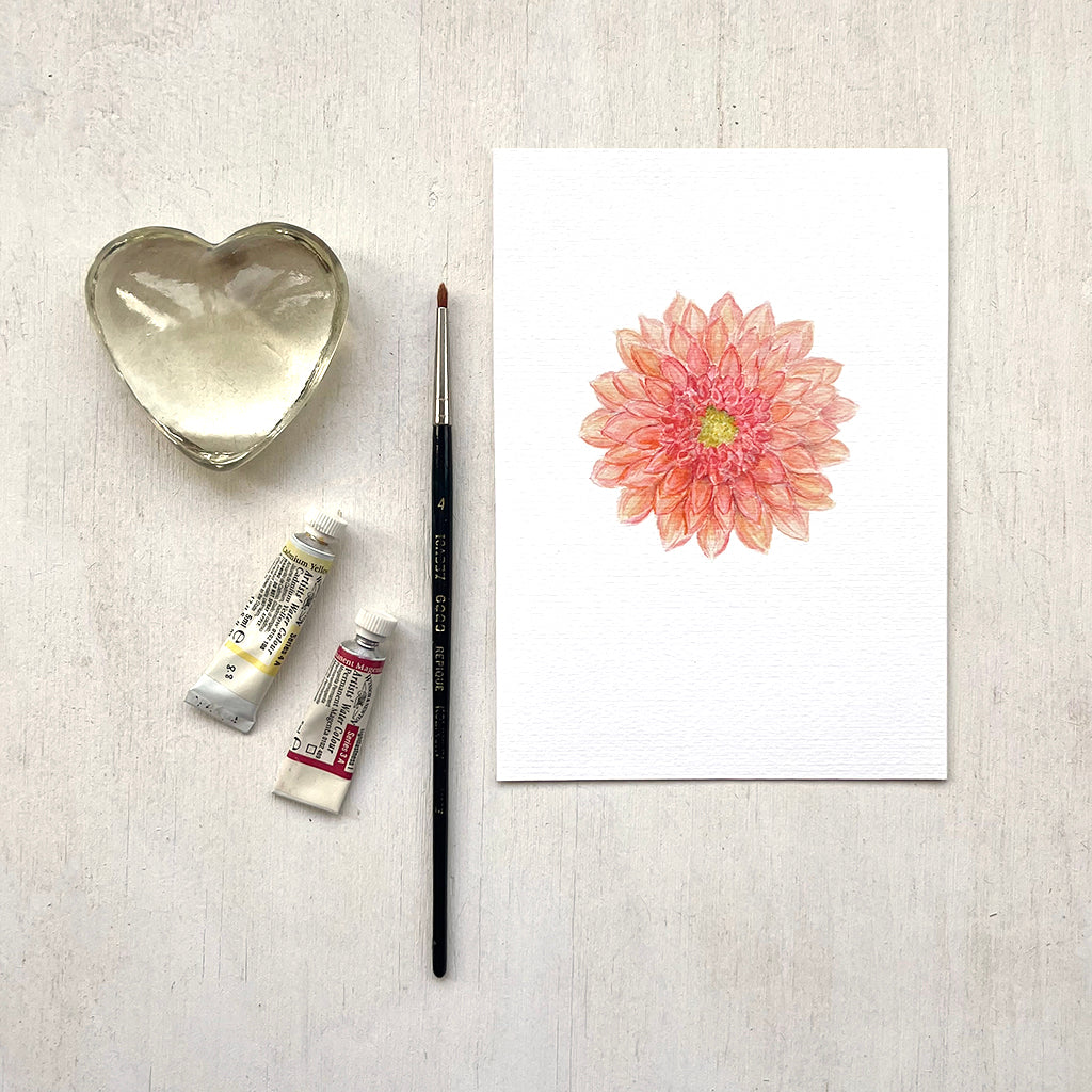 A botanical print featuring a watercolor painting of an orange-red dahlia with myriad petals.