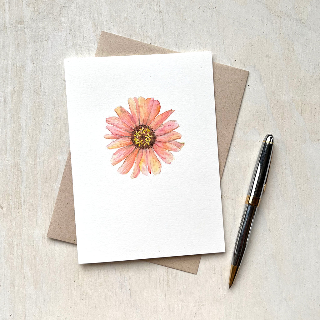 A notecard with a watercolour painting of a pretty peach-coloured zinnia by artist Kathleen Maunder.