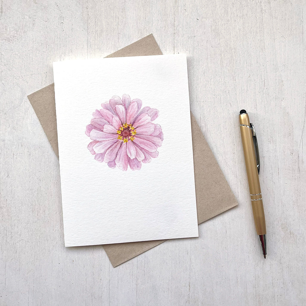 A note card featuring a delicate watercolour painting of a pink zinnia flower.